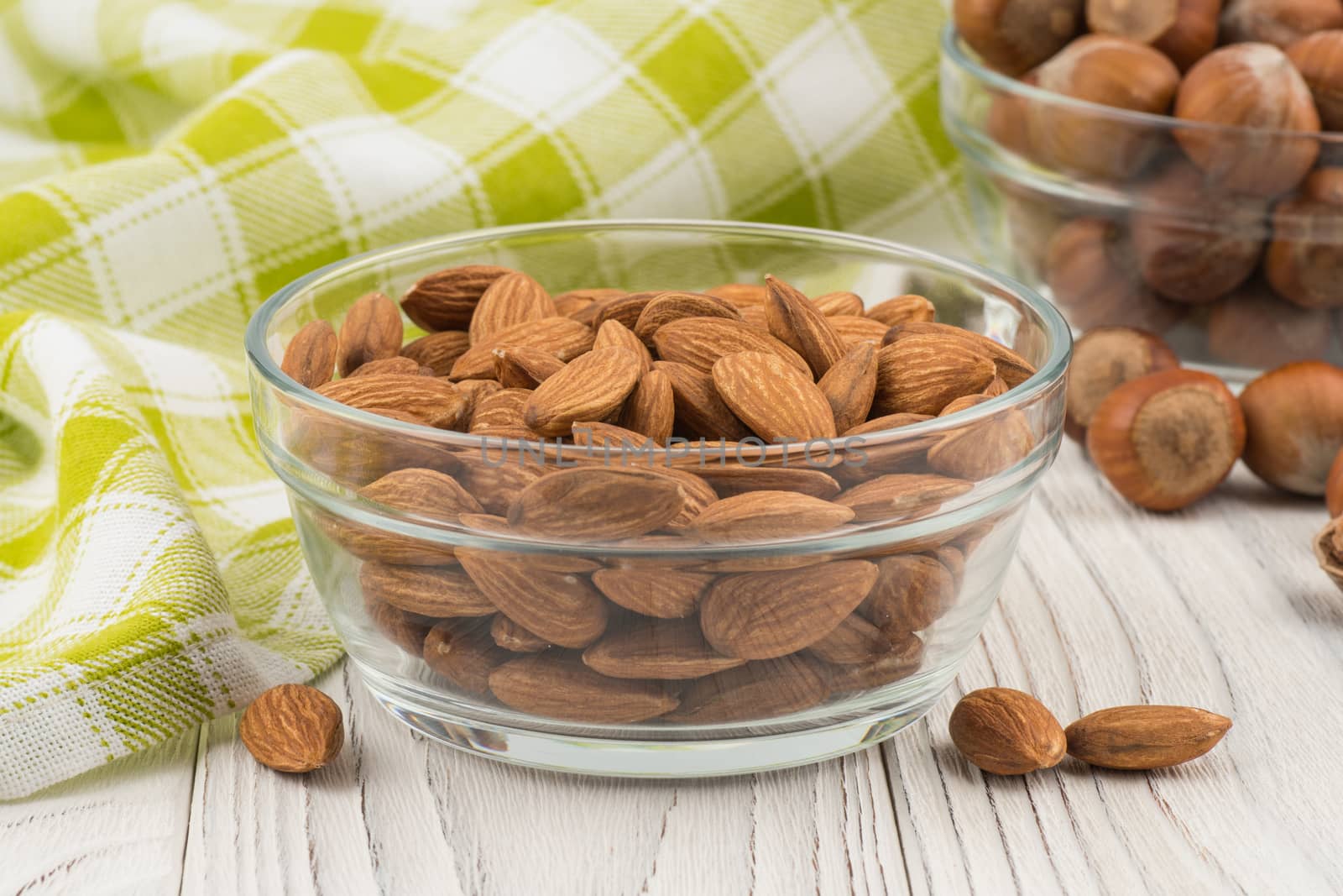 Almonds in a glass bowl on the old wooden table. Selective focus.