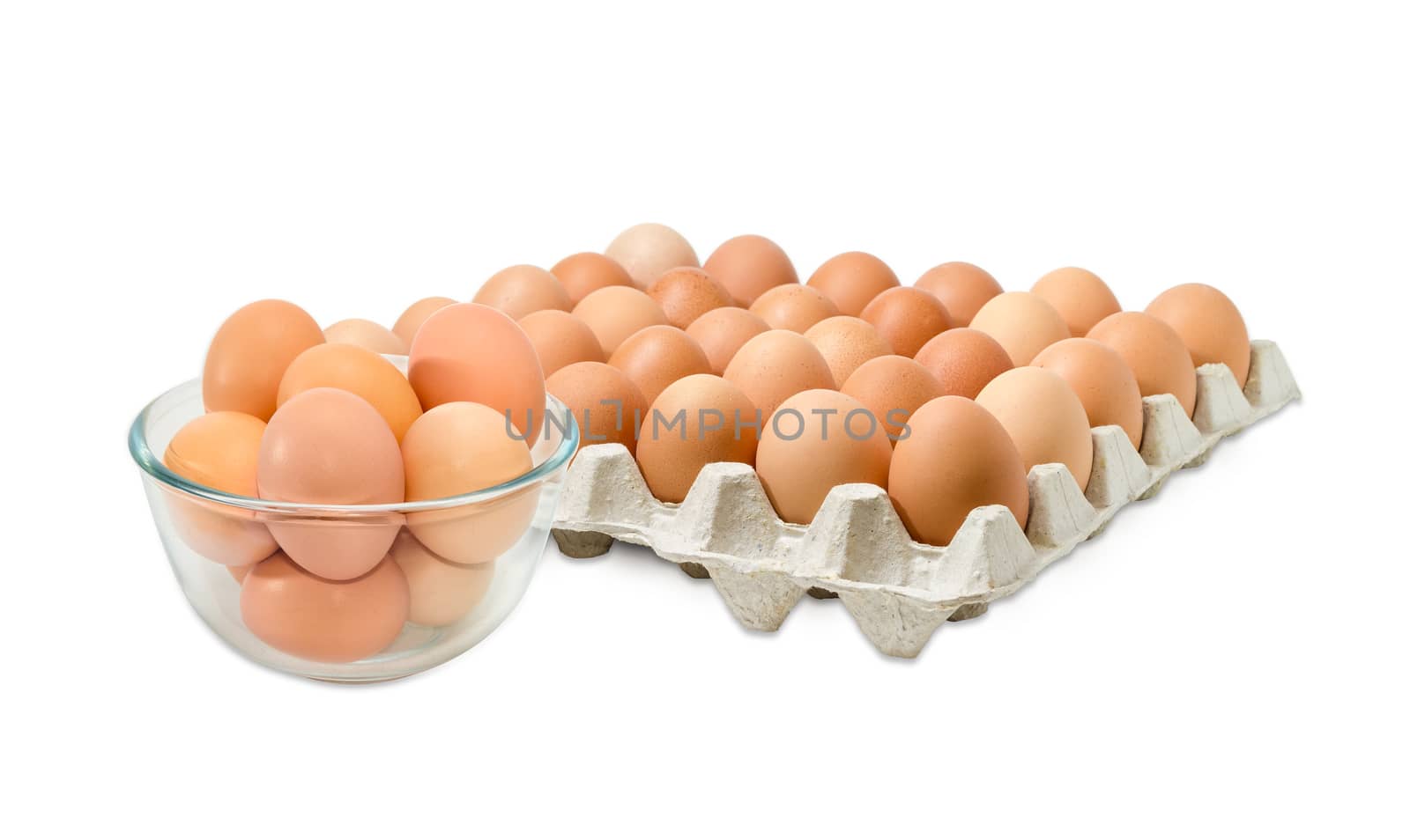 Glass bowl with the brown chicken eggs against the background of the cardboard egg tray of eggs on a light background

