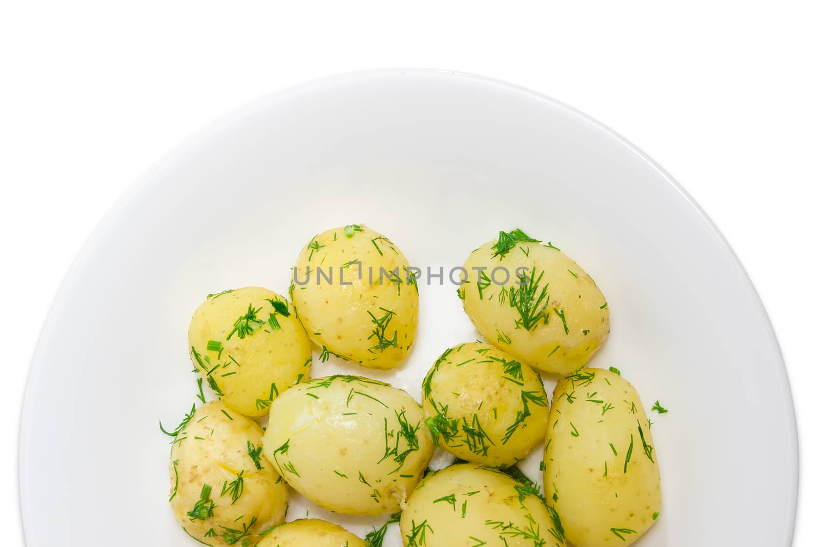 Fragment of a white dish with whole boiled young potatoes of early ripening sprinkle with the chopped dill on a light background
