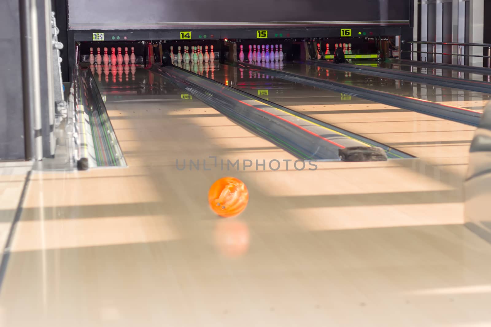 Several lanes with bowling pins and bowling ball on the foreground in a modern pin bowling alley
