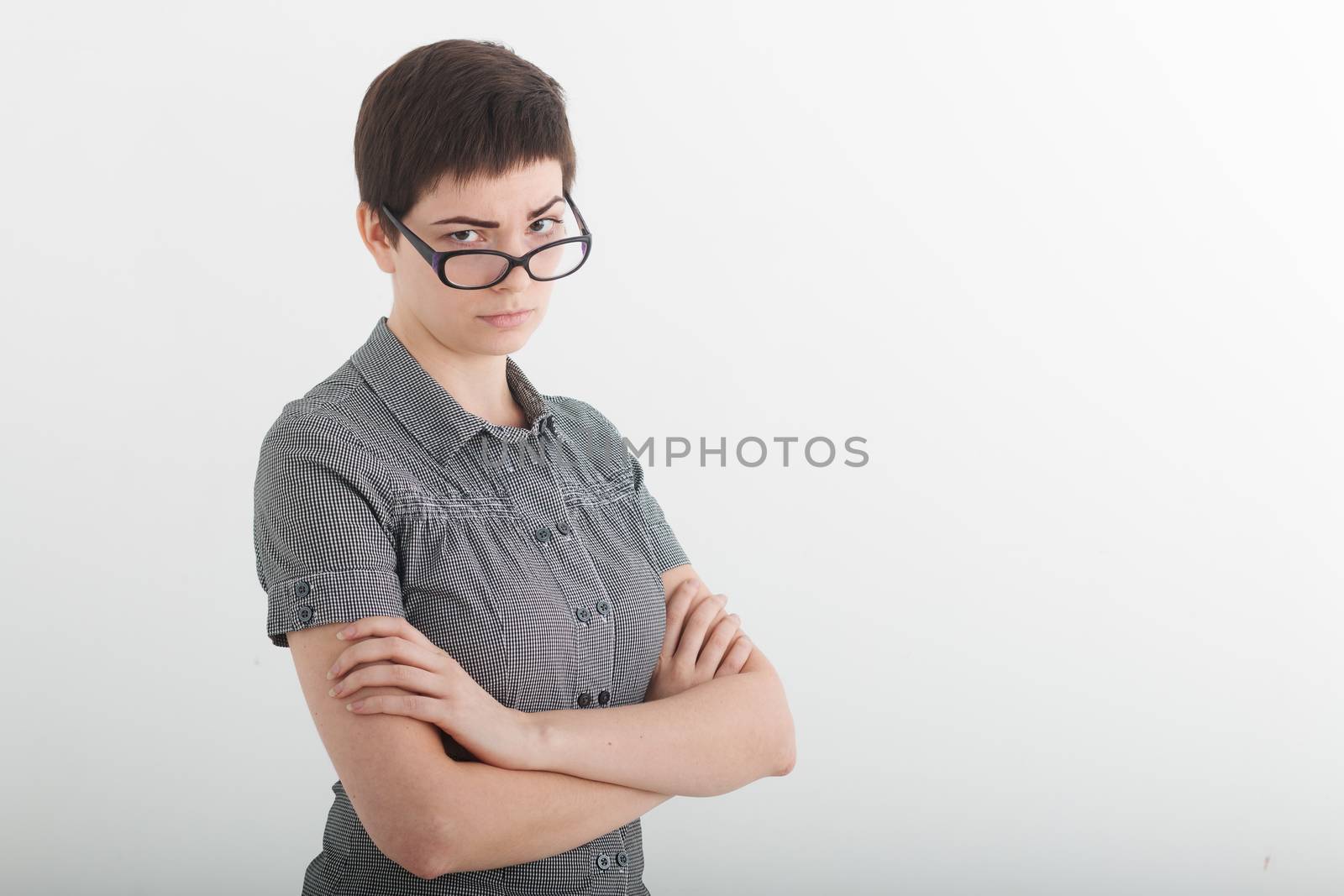 Portrait of beautiful young business woman or angry female teacher accusingly frowning over her glasses.