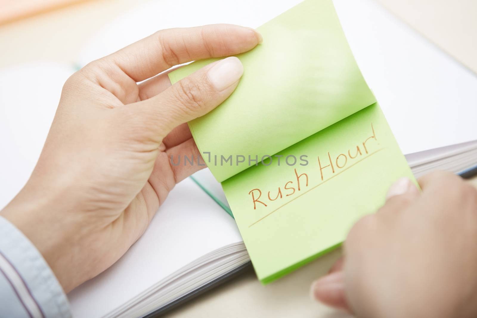 Hands holding pink sticky note with Rush hour text