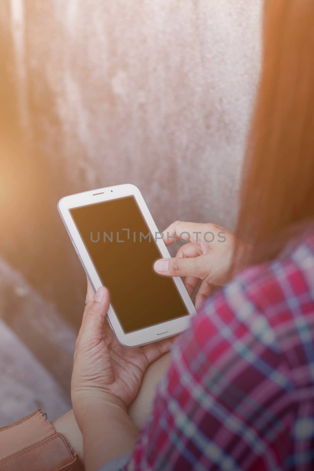 woman using a cell phone next to a wall.