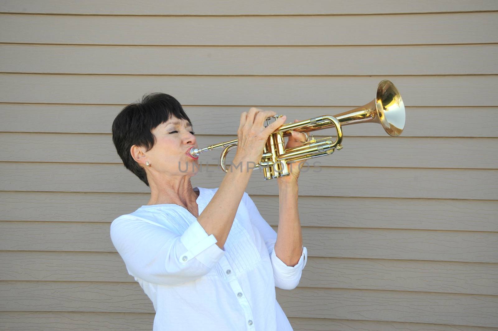Mature female beauty blowing her trumpet outside.