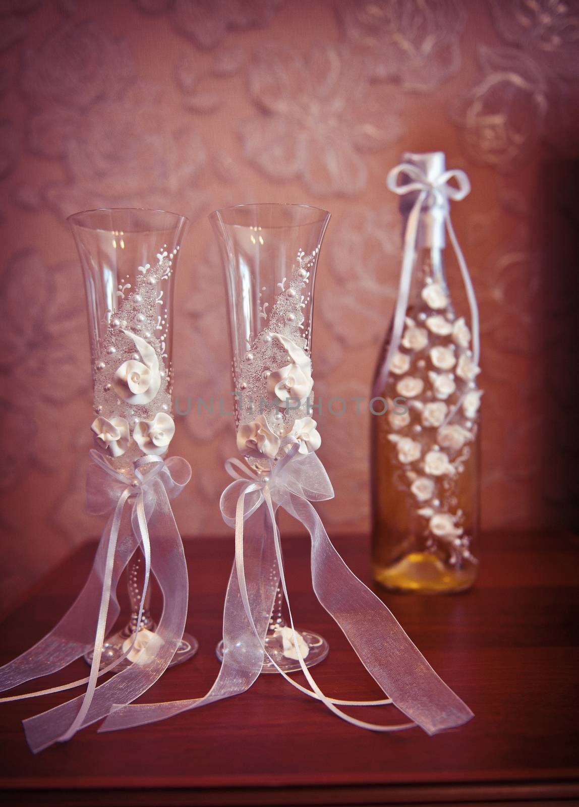 Two wedding glasses and a bottle of champagne on the table.