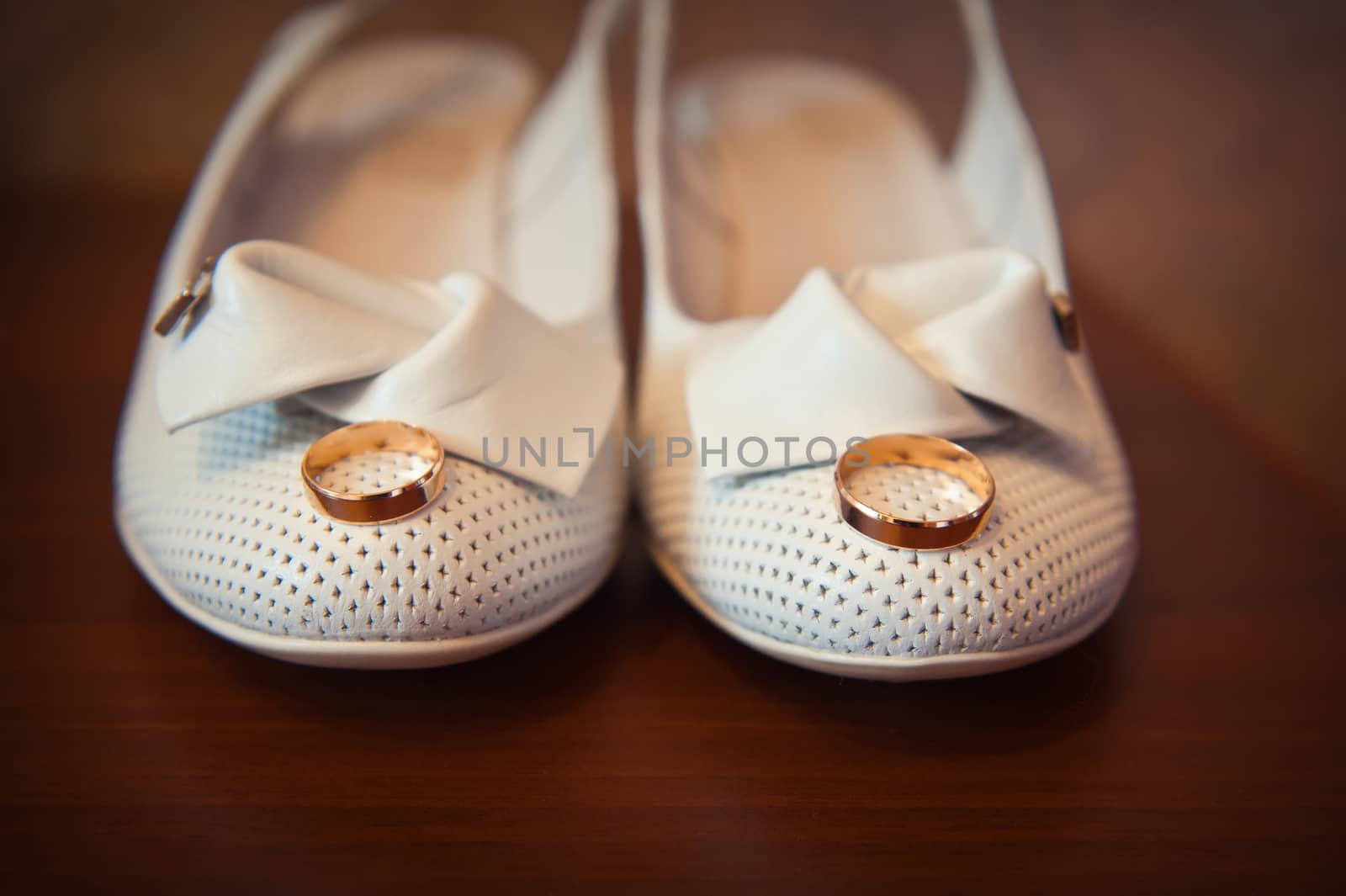 gold ring on the bride's white shoes closeup.