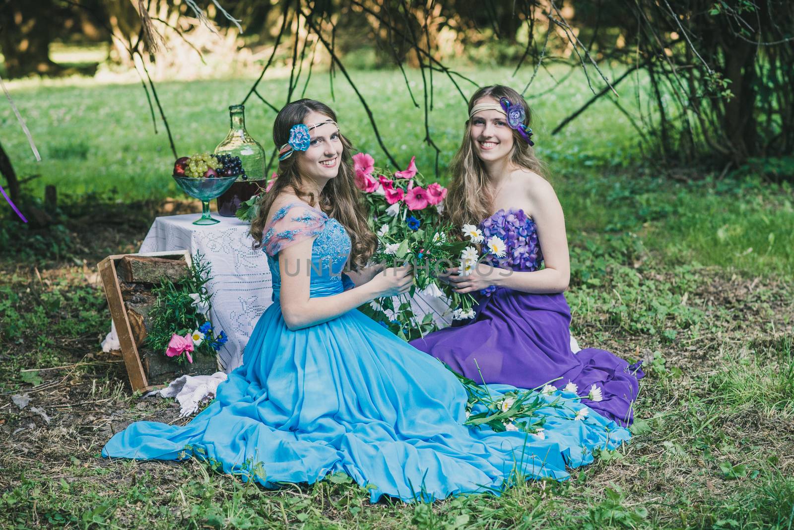 two adult sisters are twins with flowers in the summer garden