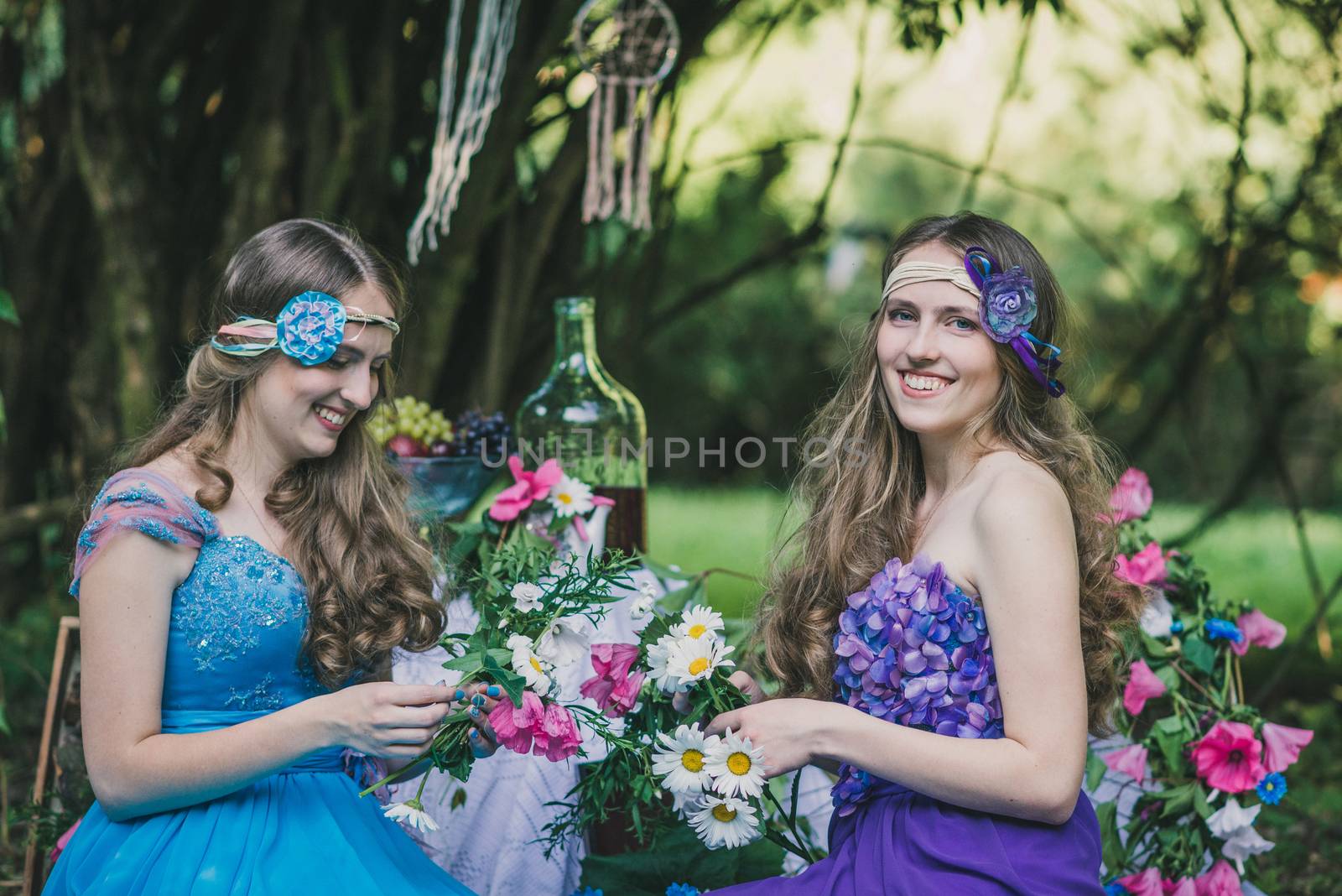 two adult sisters are twins with flowers in the summer garden