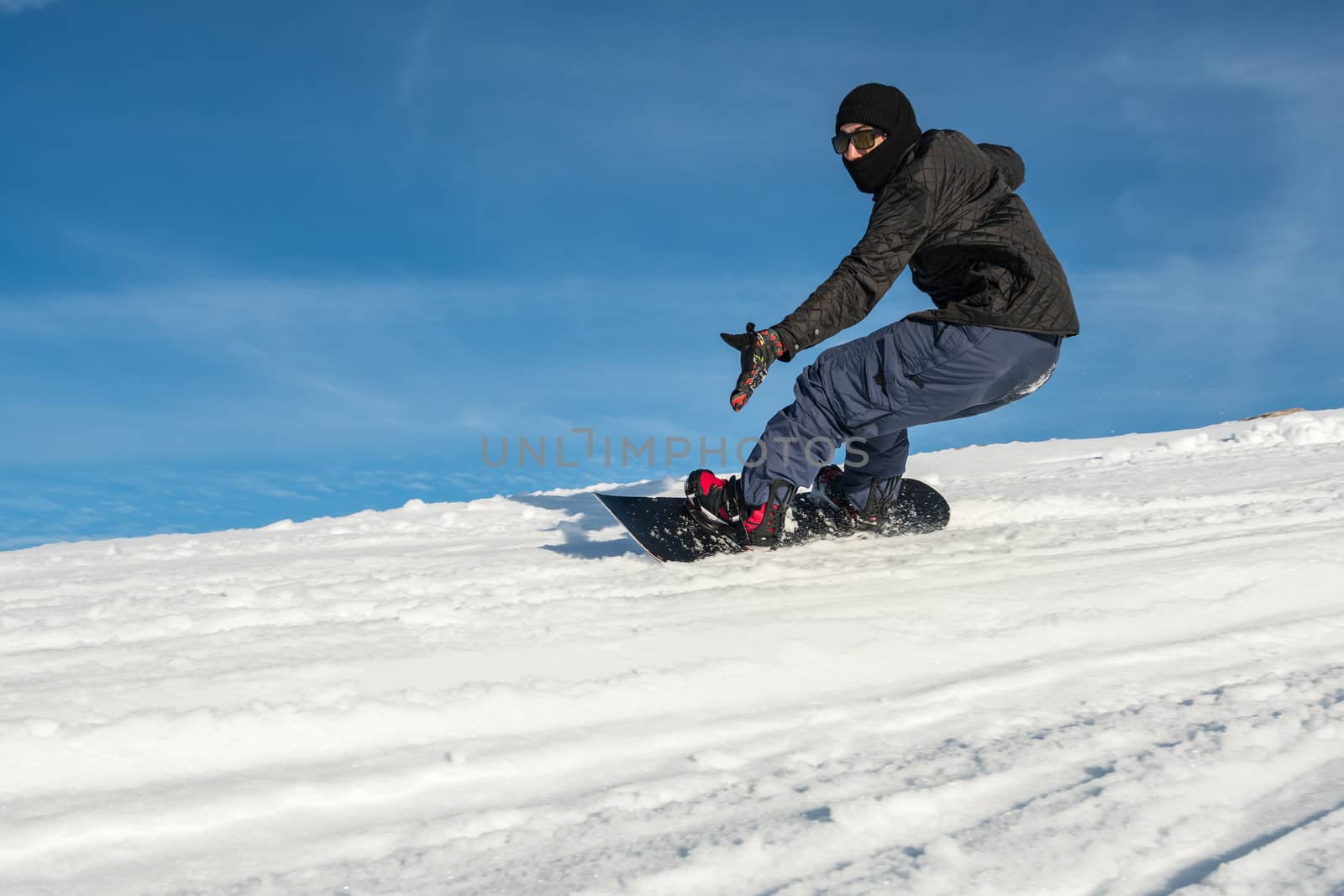 Snowboard freerider in the mountains against in blue sky.