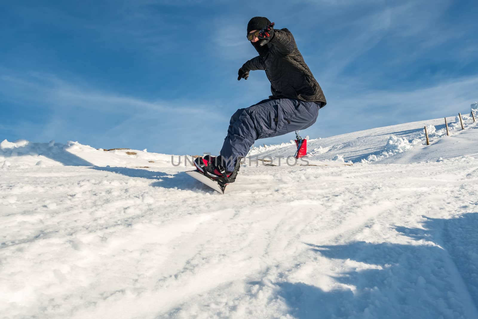 Snowboard freerider in the mountains against in blue sky.