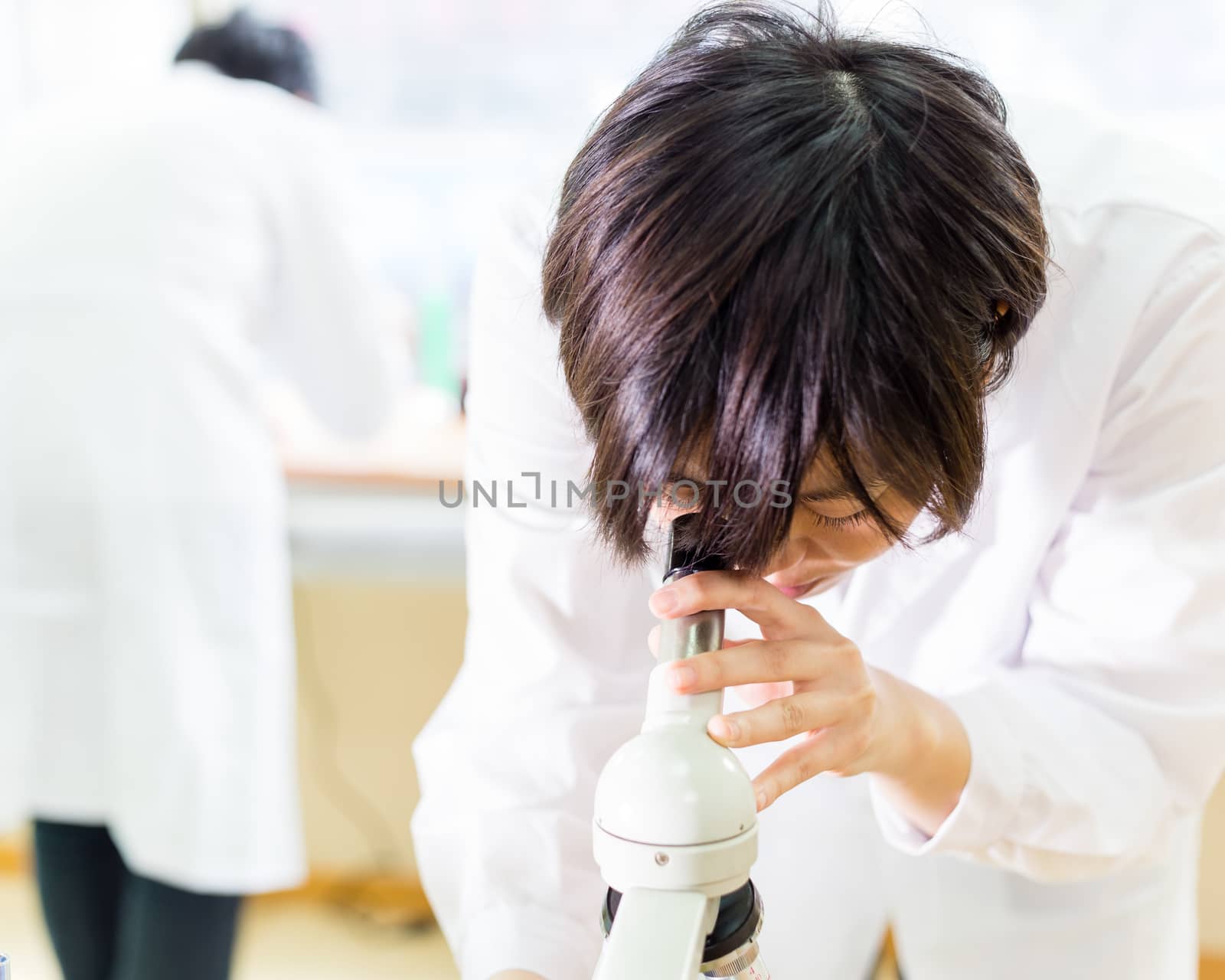 Asian female scientist looking into microscope by imagesbykenny