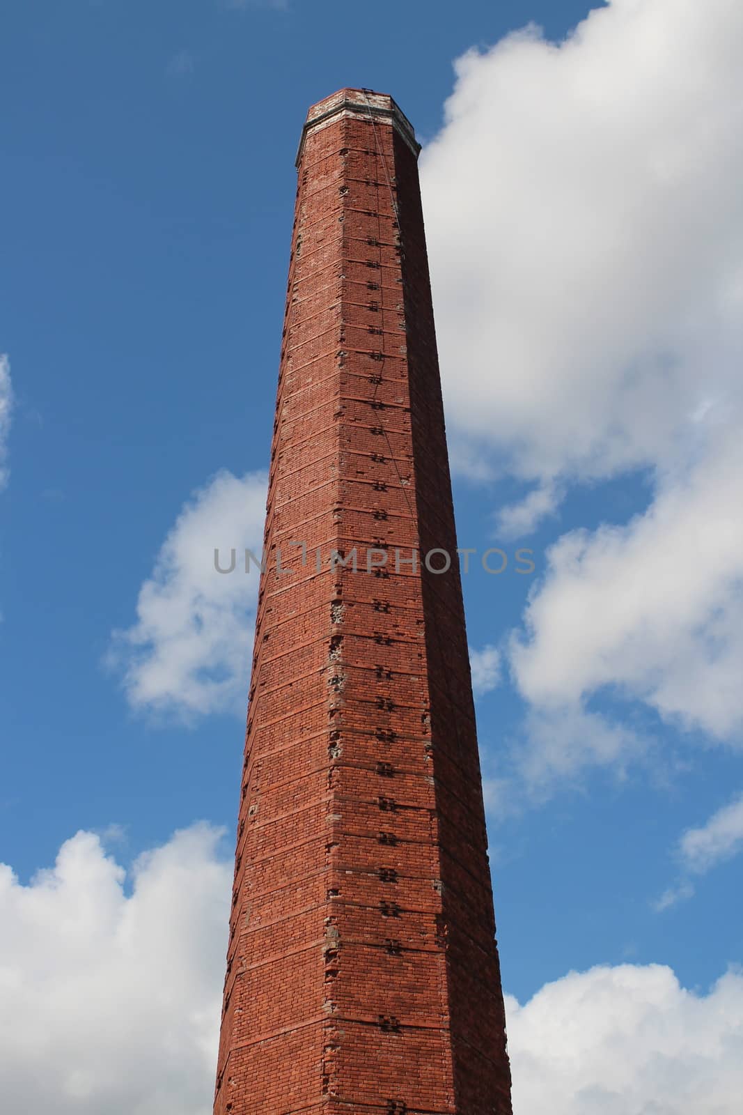High brick smokestack in the blue sky by mrivserg