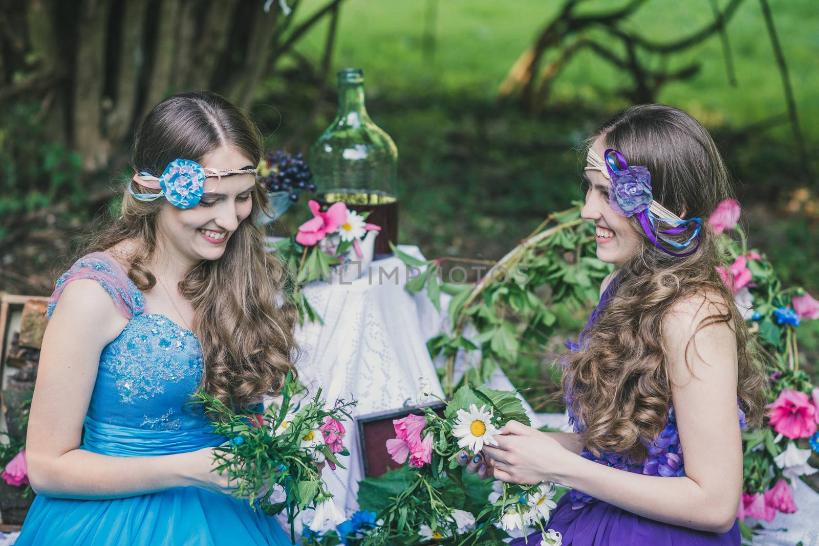 two adult sisters are twins with flowers in the summer garden