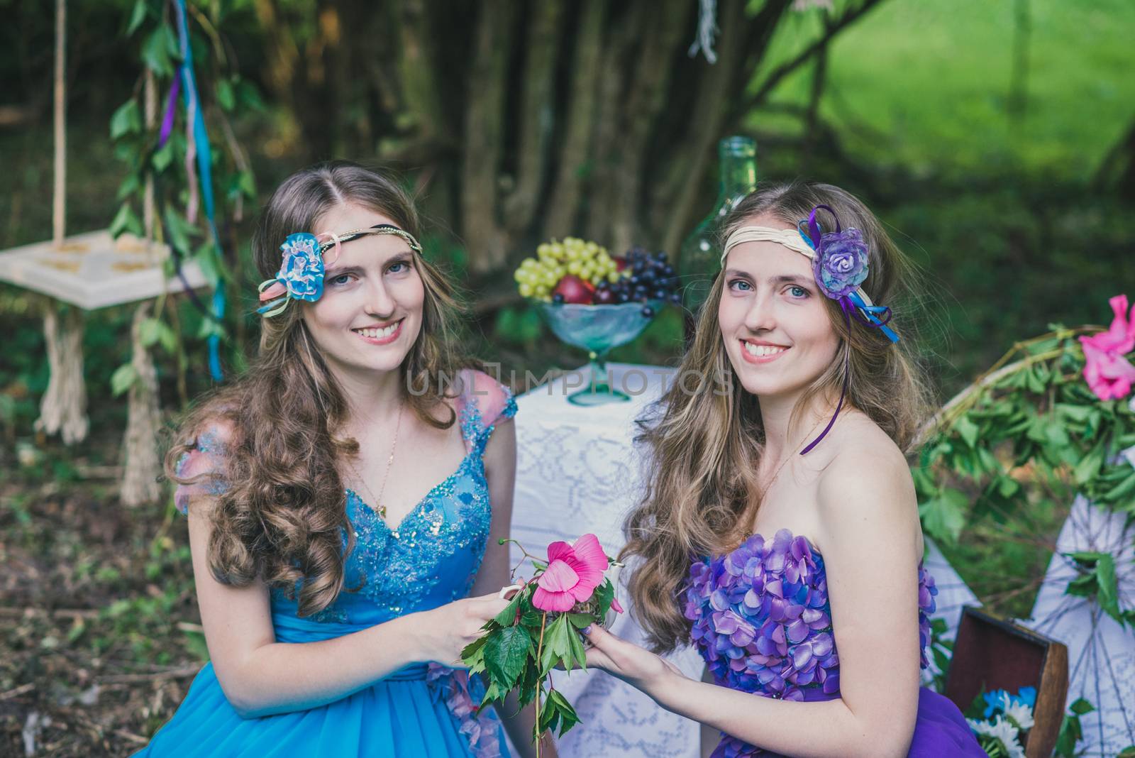 two adult sisters are twins with flowers in the summer garden