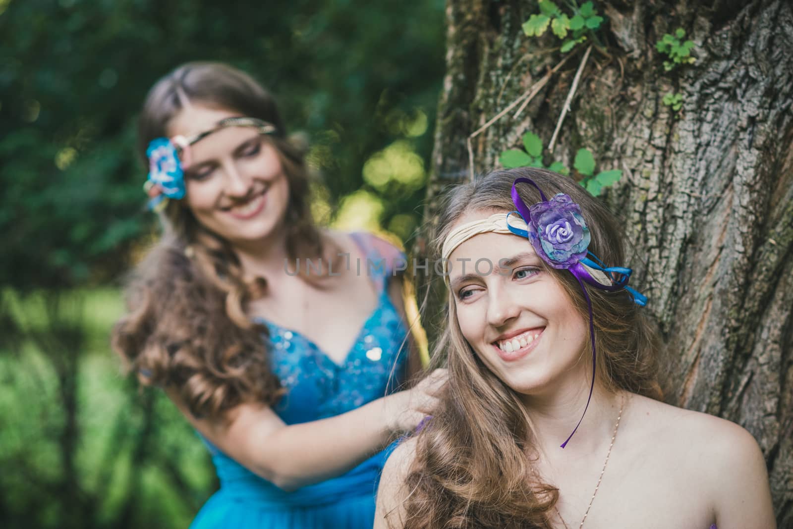 two sisters, twins from near tree in summer