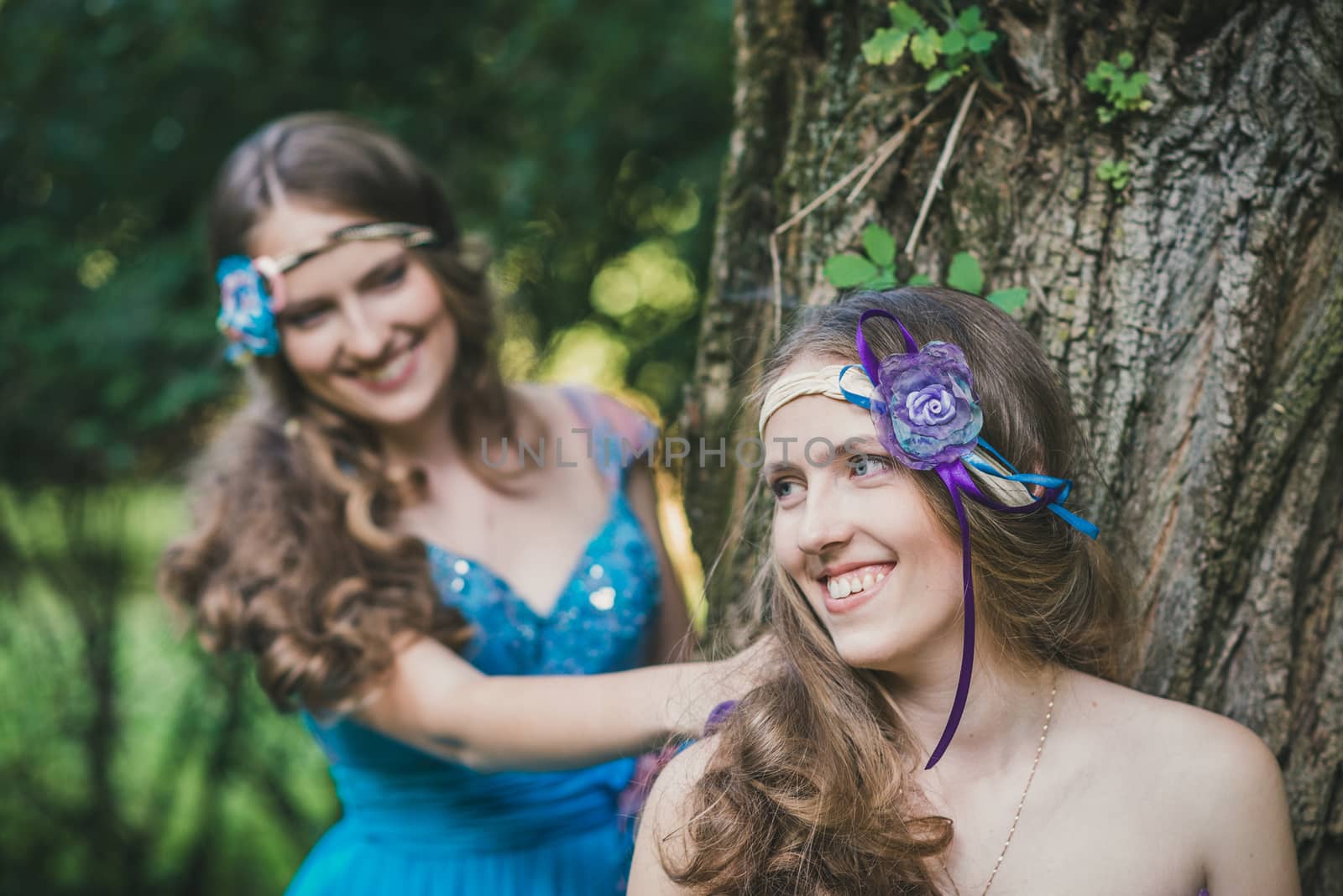 two sisters, twins at the green tree in summer