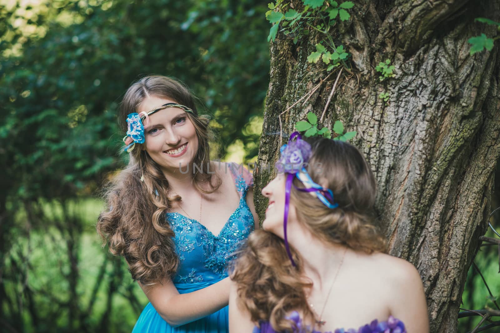 two sisters, twins from near tree in summer