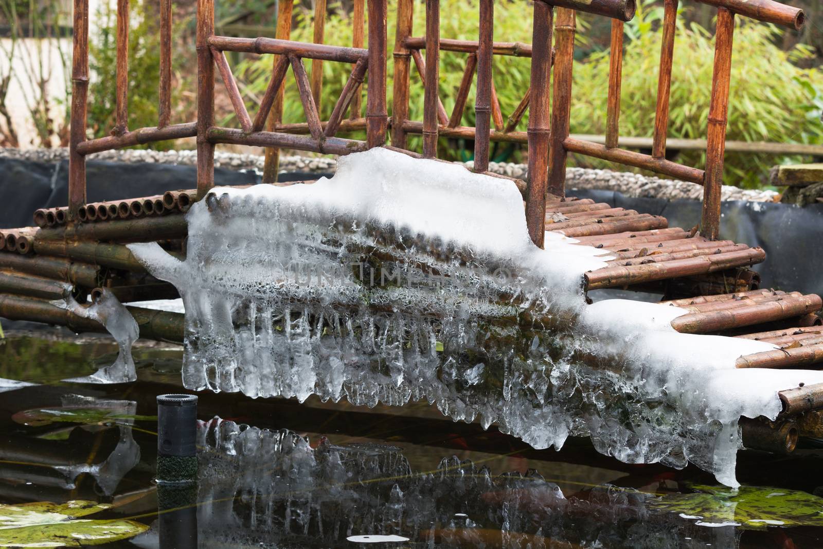 Icicles hanging from a bridge over a frozen lake.