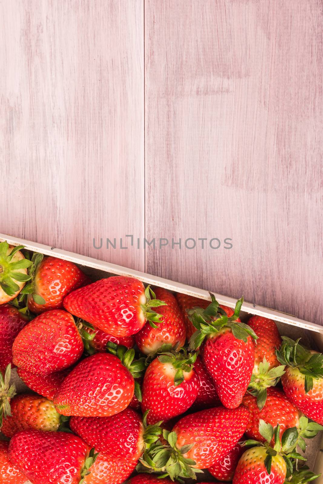 Fresh strawberries in wooden basket on wooden table. Top view with copy space