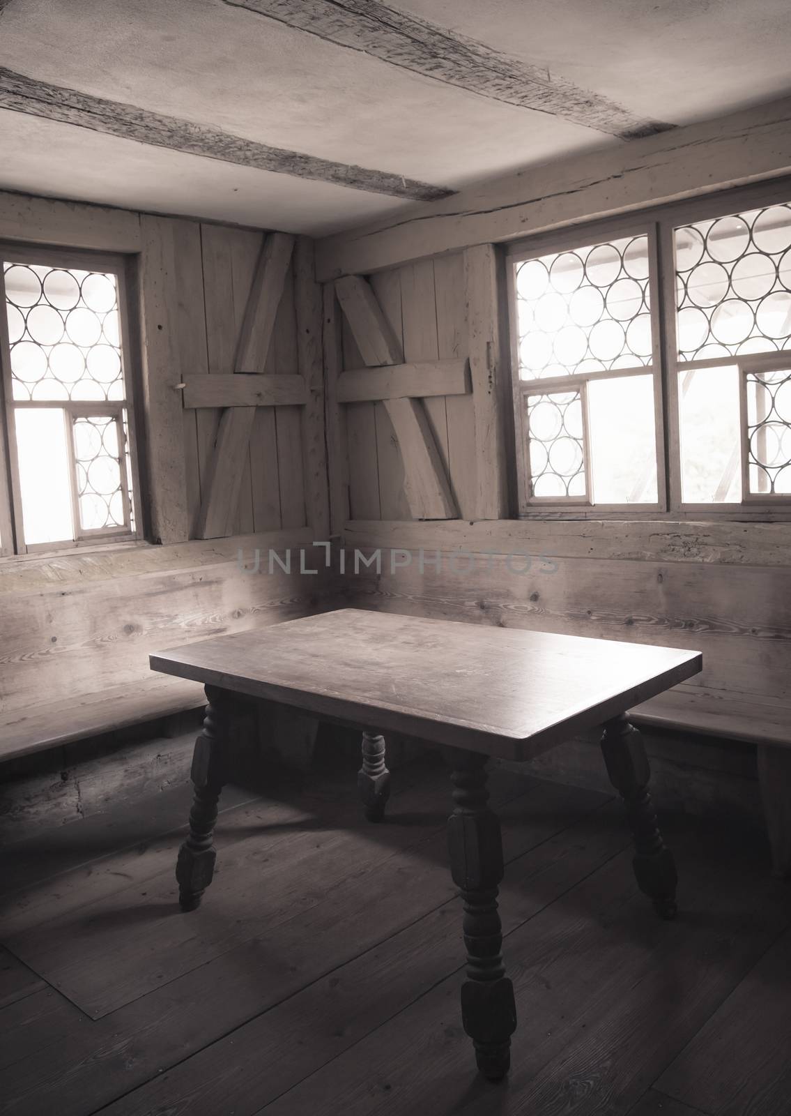 Retro style image with monochrome settings of an aged dining room interior with wooden furniture, walls and floor, depicting the rural life in medieval times.