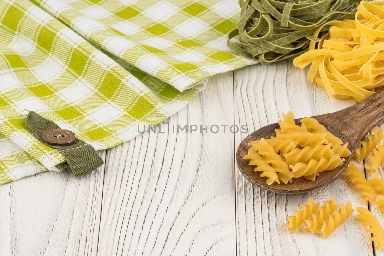 Pasta in a wooden spoon on old wooden table. Selective focus.