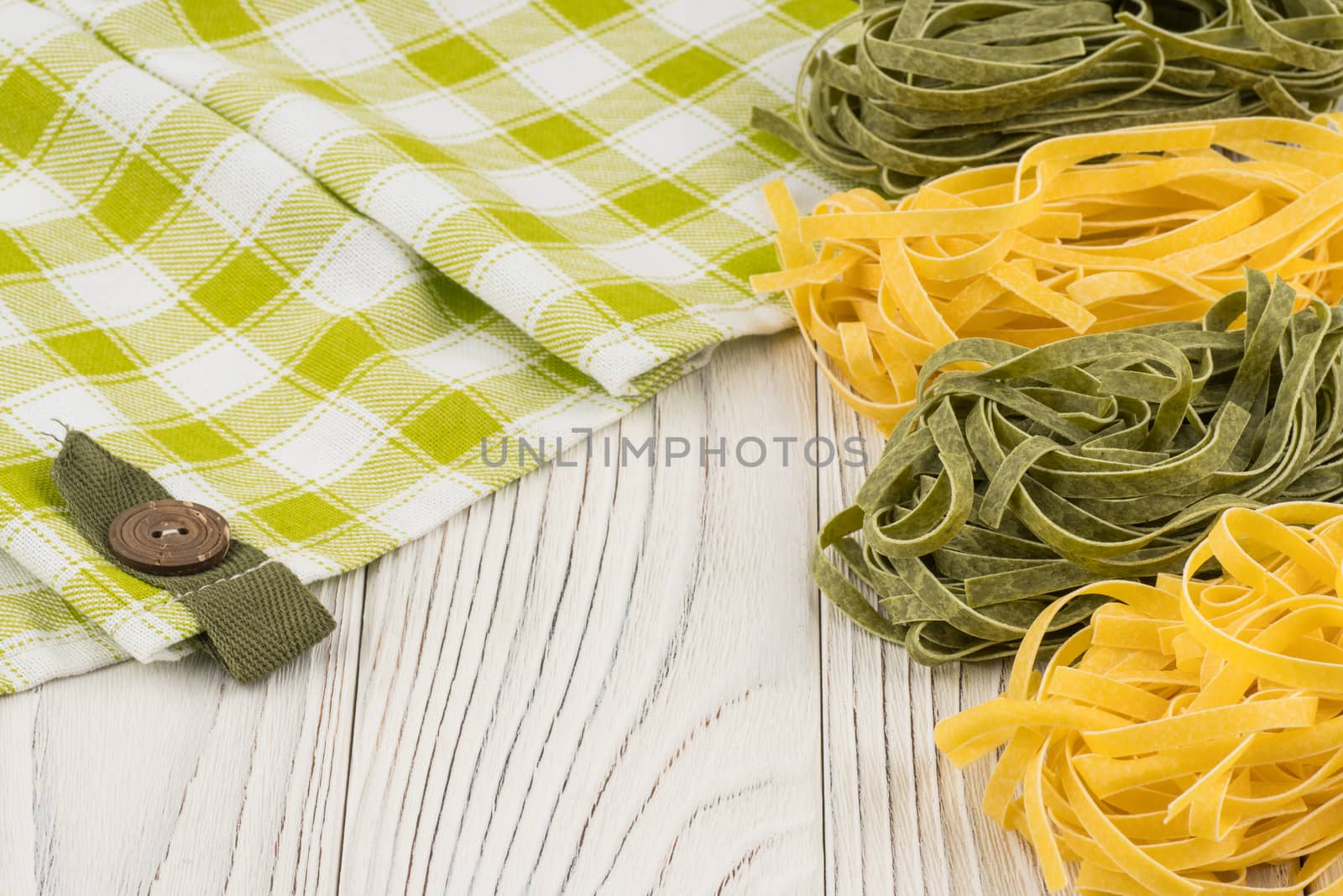 Raw green and yellow pasta on an old white wooden table. Selective focus.