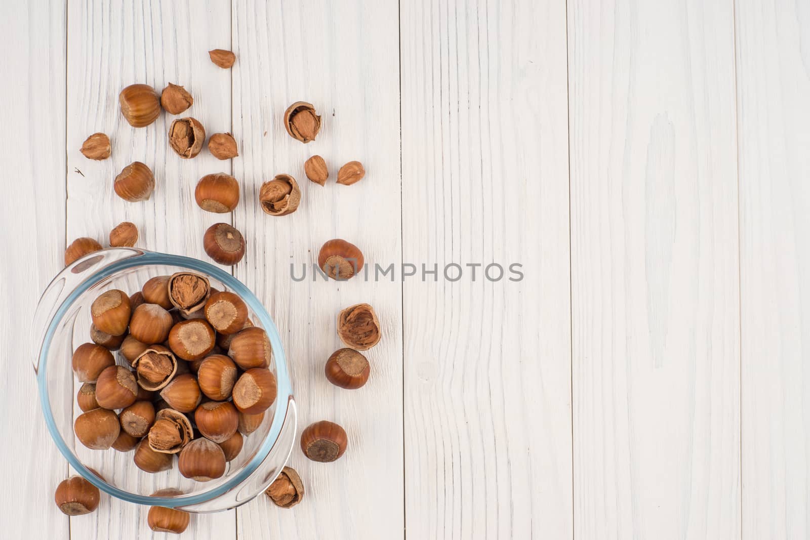 Hazelnut in a glass bowl on the old wooden table. Top view.