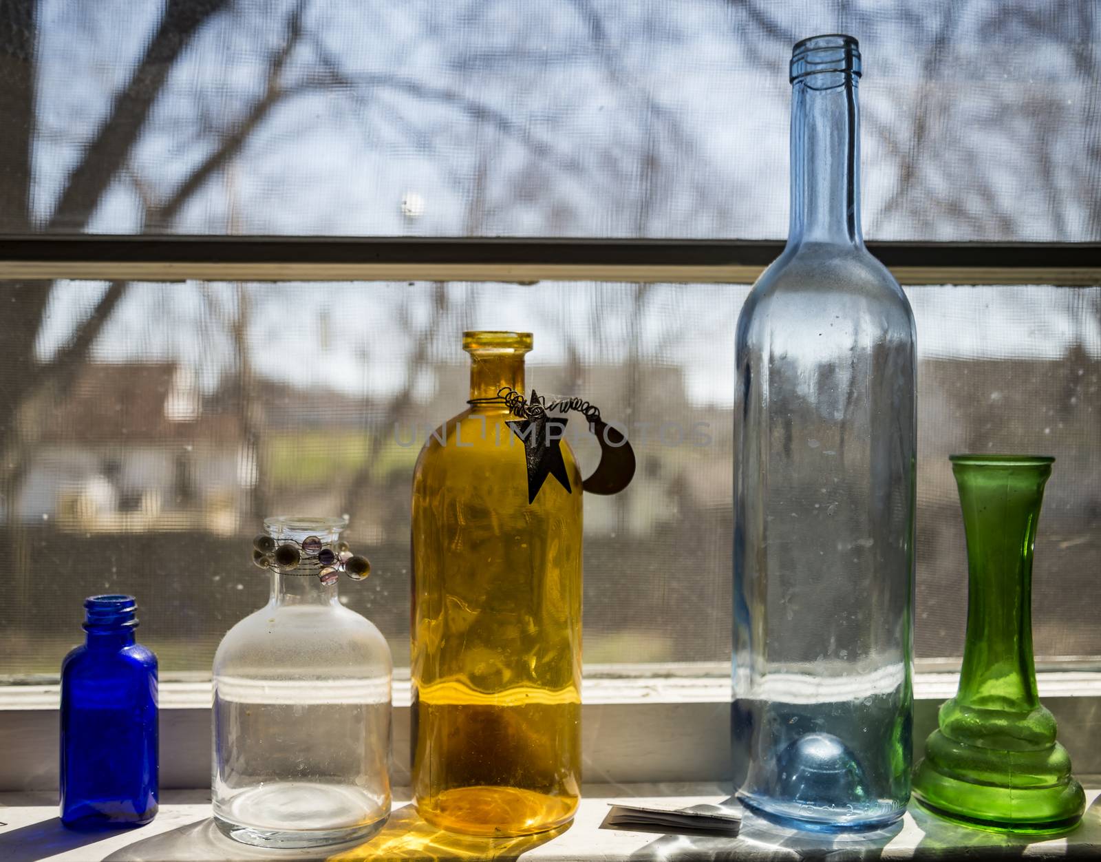 Five colored bottles isolated over a window