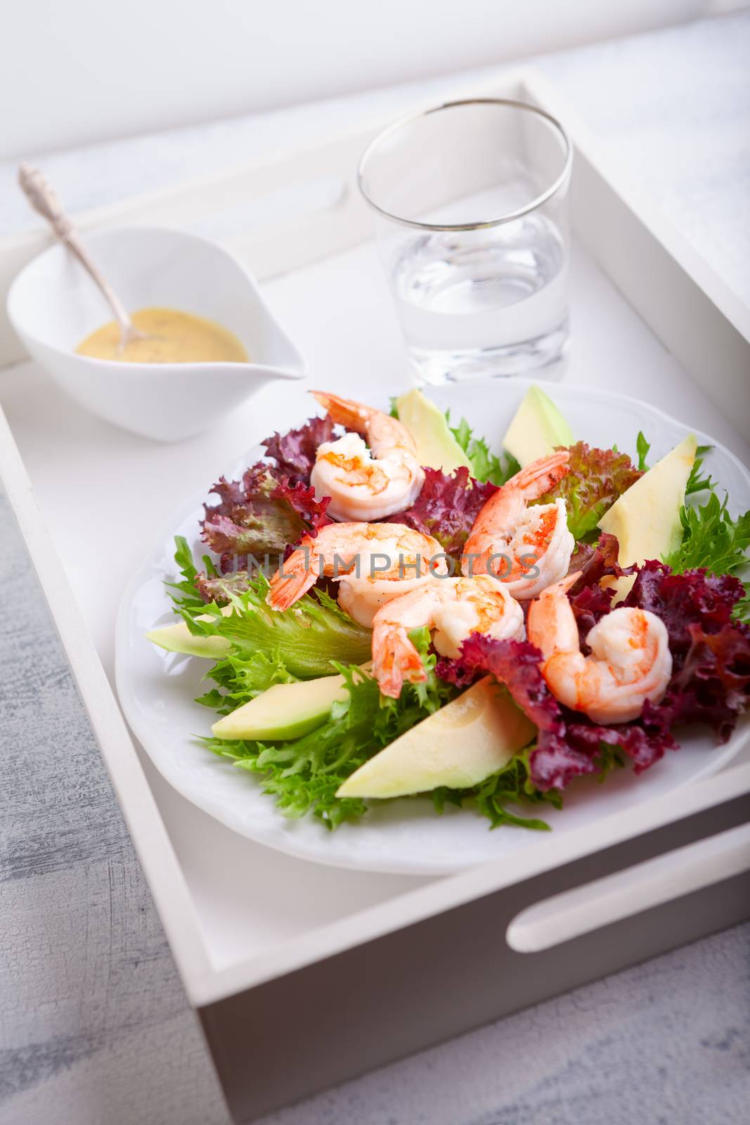 Avocado shrimp salad with mustard sauce on a tray.