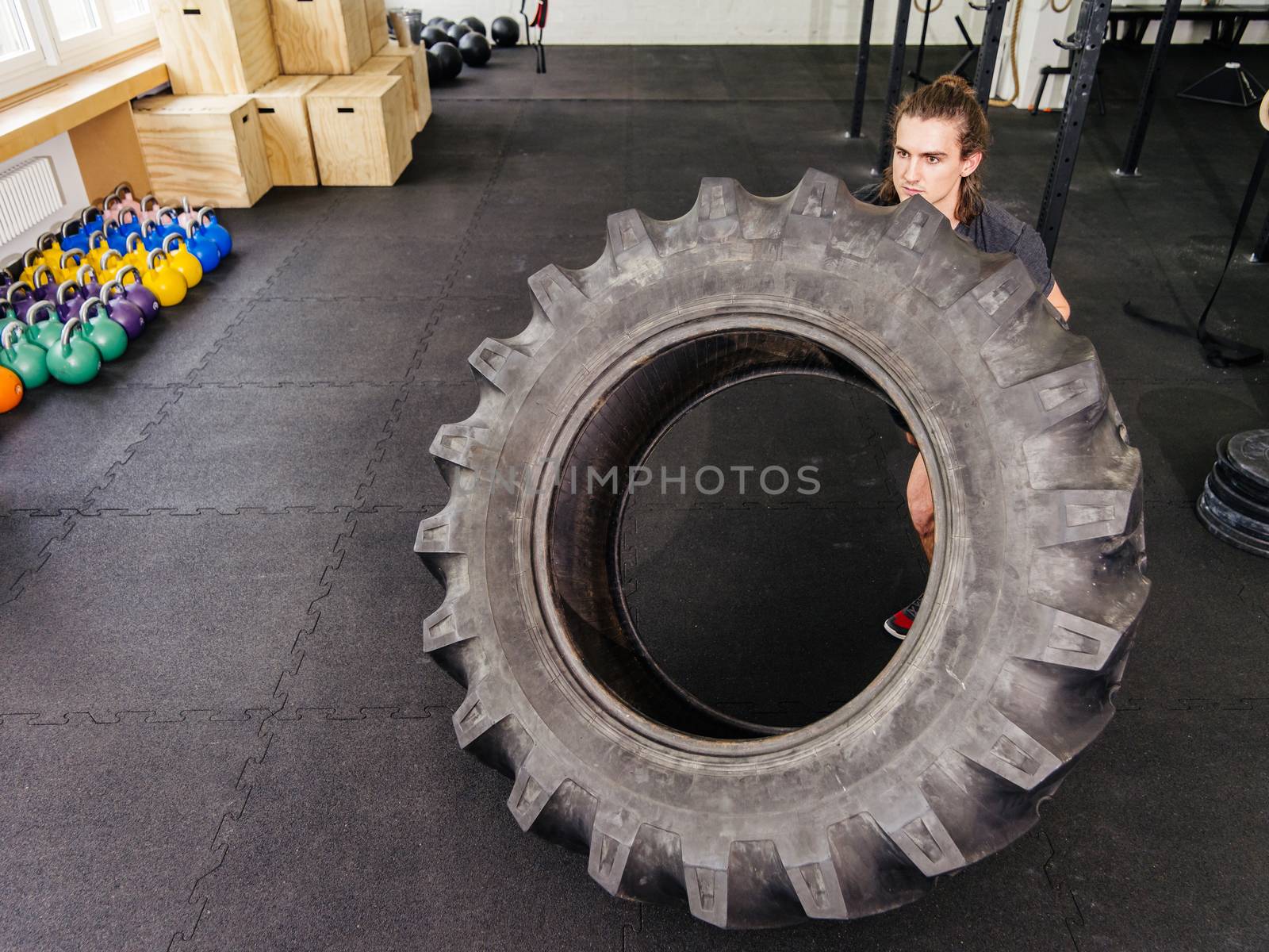 Man exercising with a tractor tire at gym by sumners