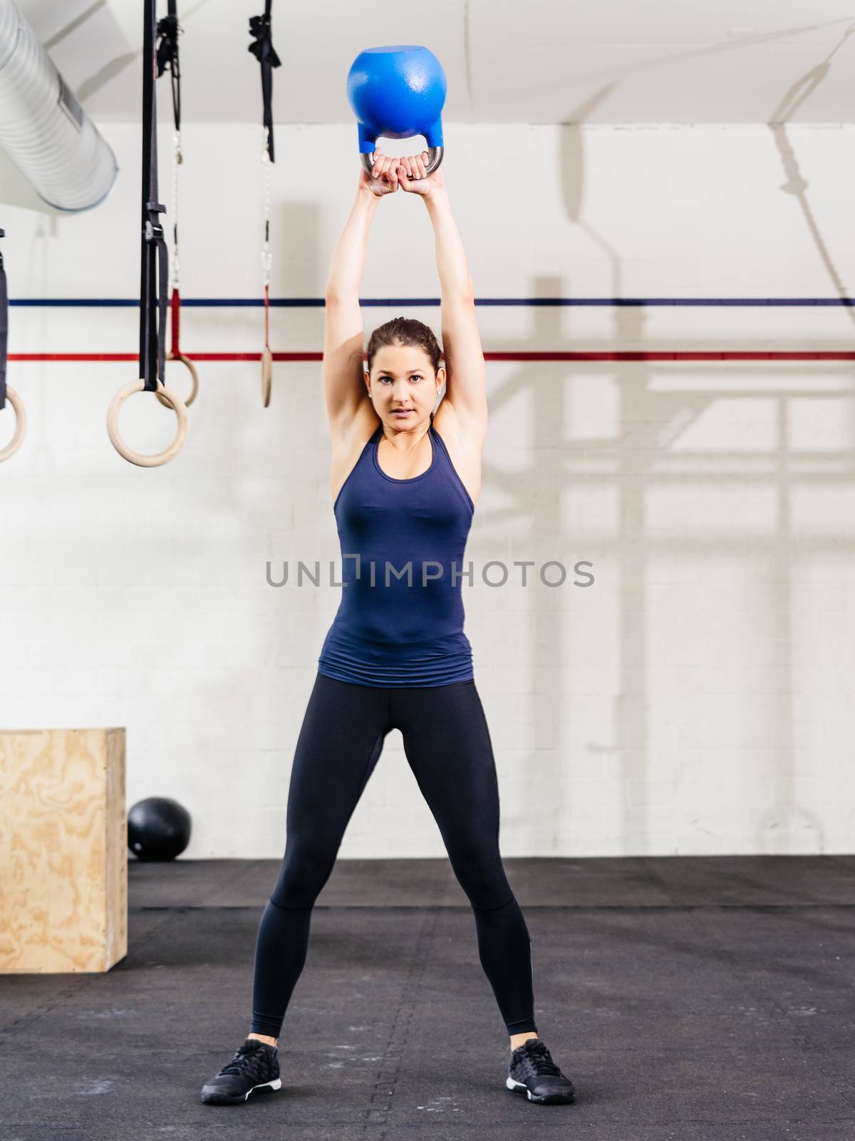 Photo of a young woman exercising with a kettle bell at a gym. 