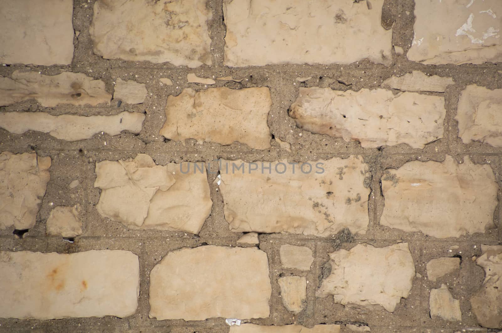 Rugged old limestone wall that is uneven, rustic and filled with cement mortar.