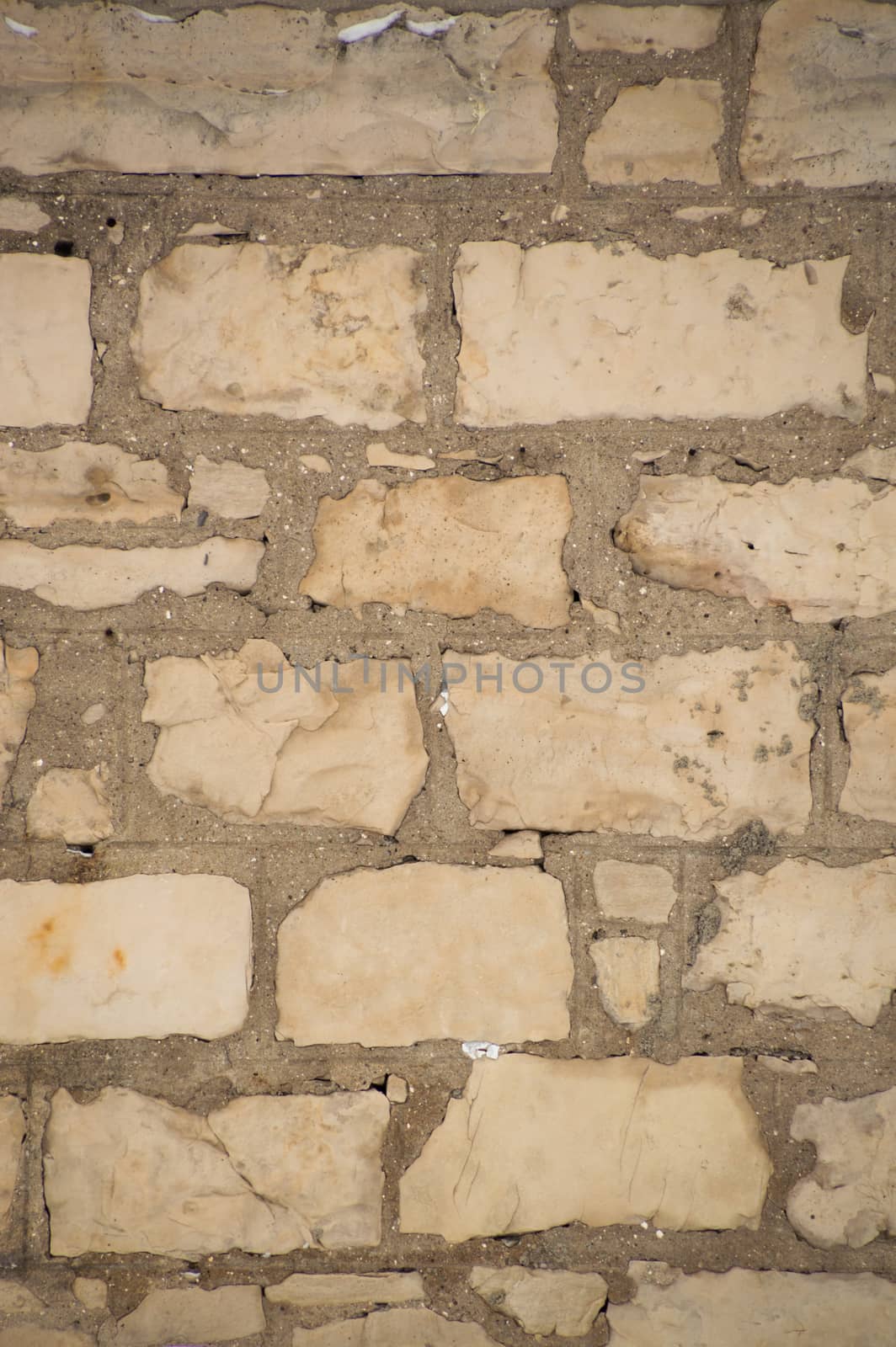 Rugged old limestone wall that is uneven, rustic and filled with cement mortar.