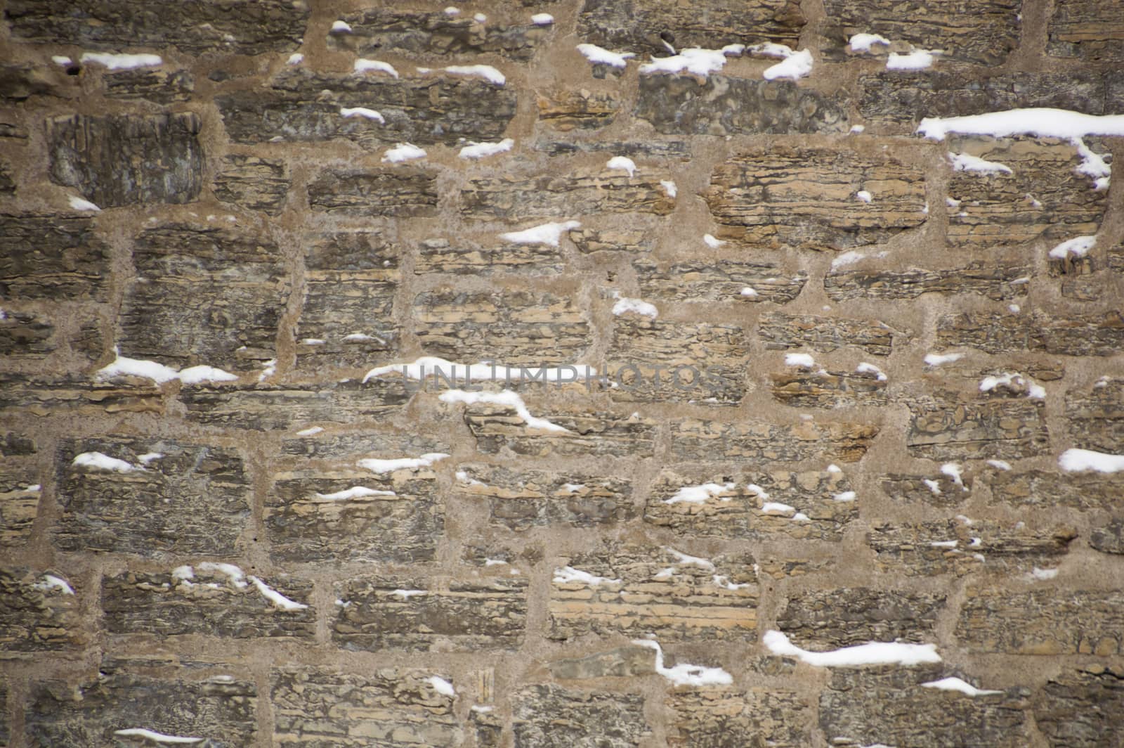 Snowy limestone stone wall with mortar in winter by Sublimage