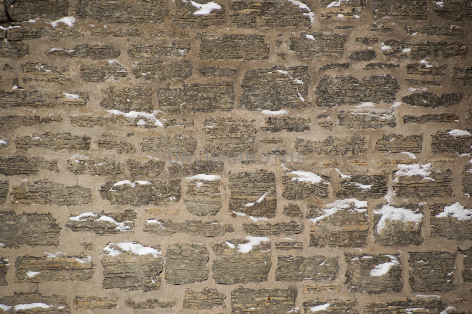 Snowy limestone stone wall with mortar in winter by Sublimage