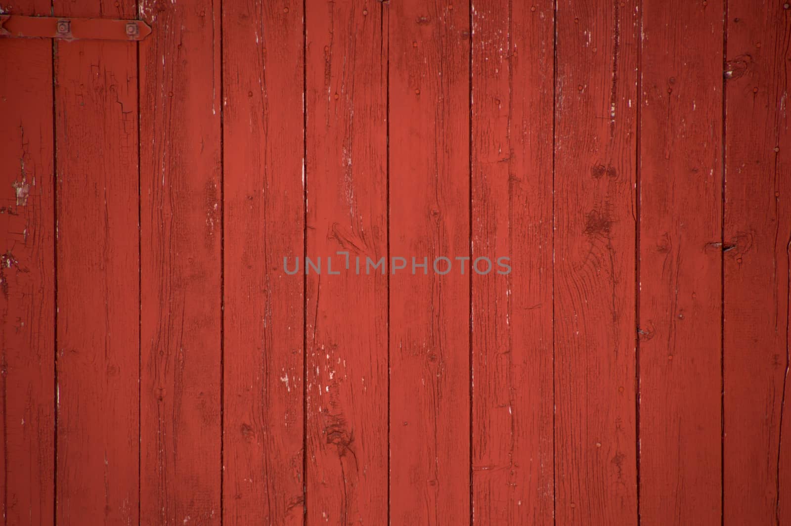 Vertical oxblood red barn door boards and planks background. One red hinge.