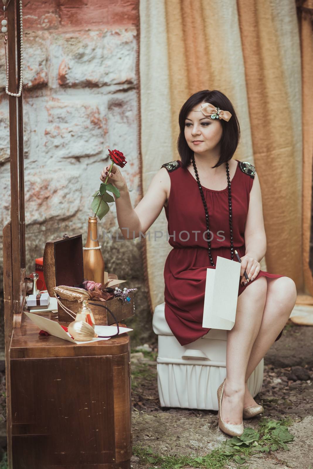 retro girl sitting at a dressing table with a letter and red rose in your hands