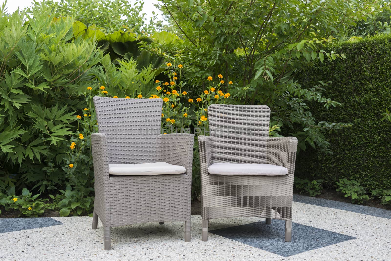terrace with rattan relax chairs in garden with flowers as background
