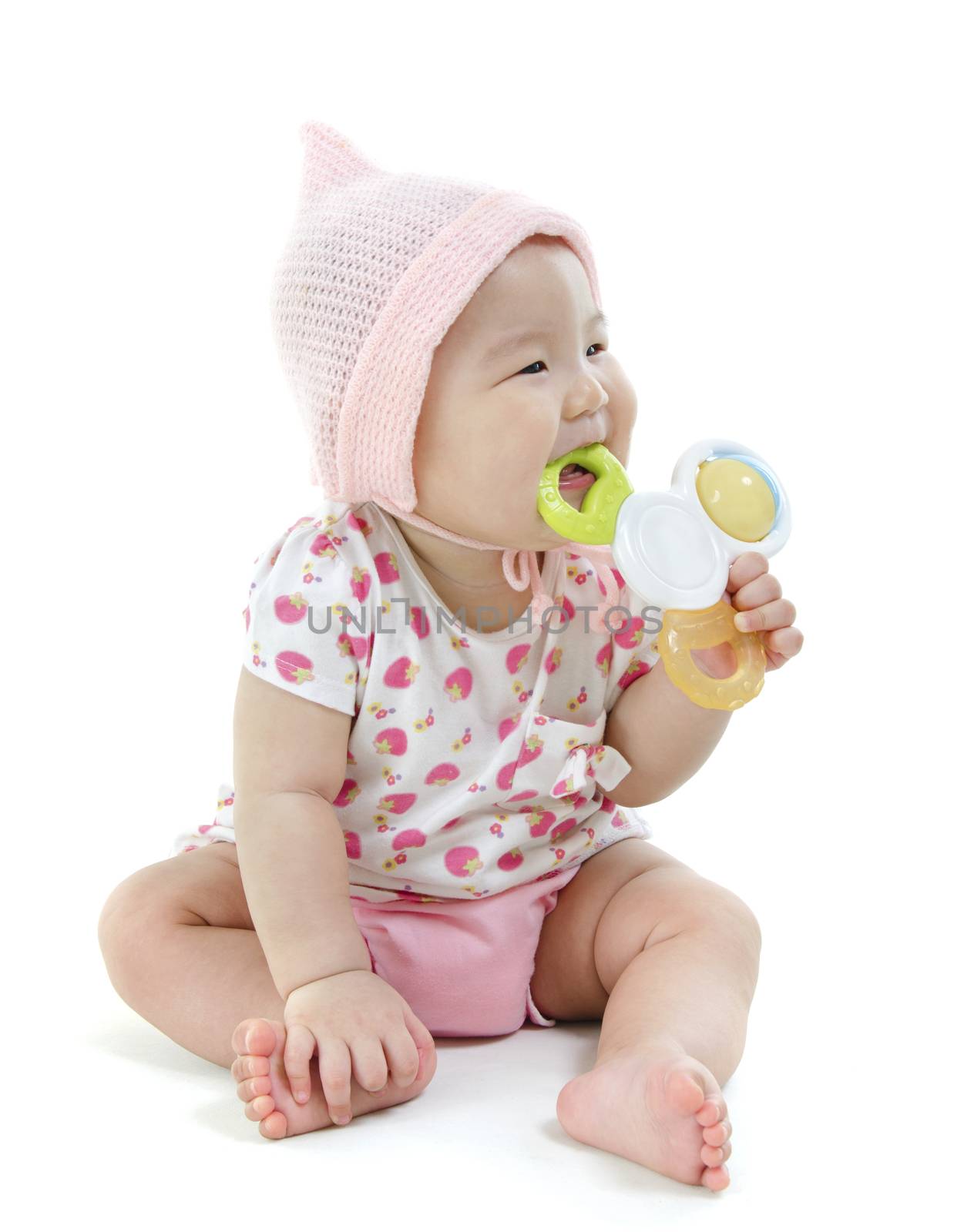 Portrait of full length beautiful Asian baby girl in pink clothes biting teether toy, isolated on white background.
