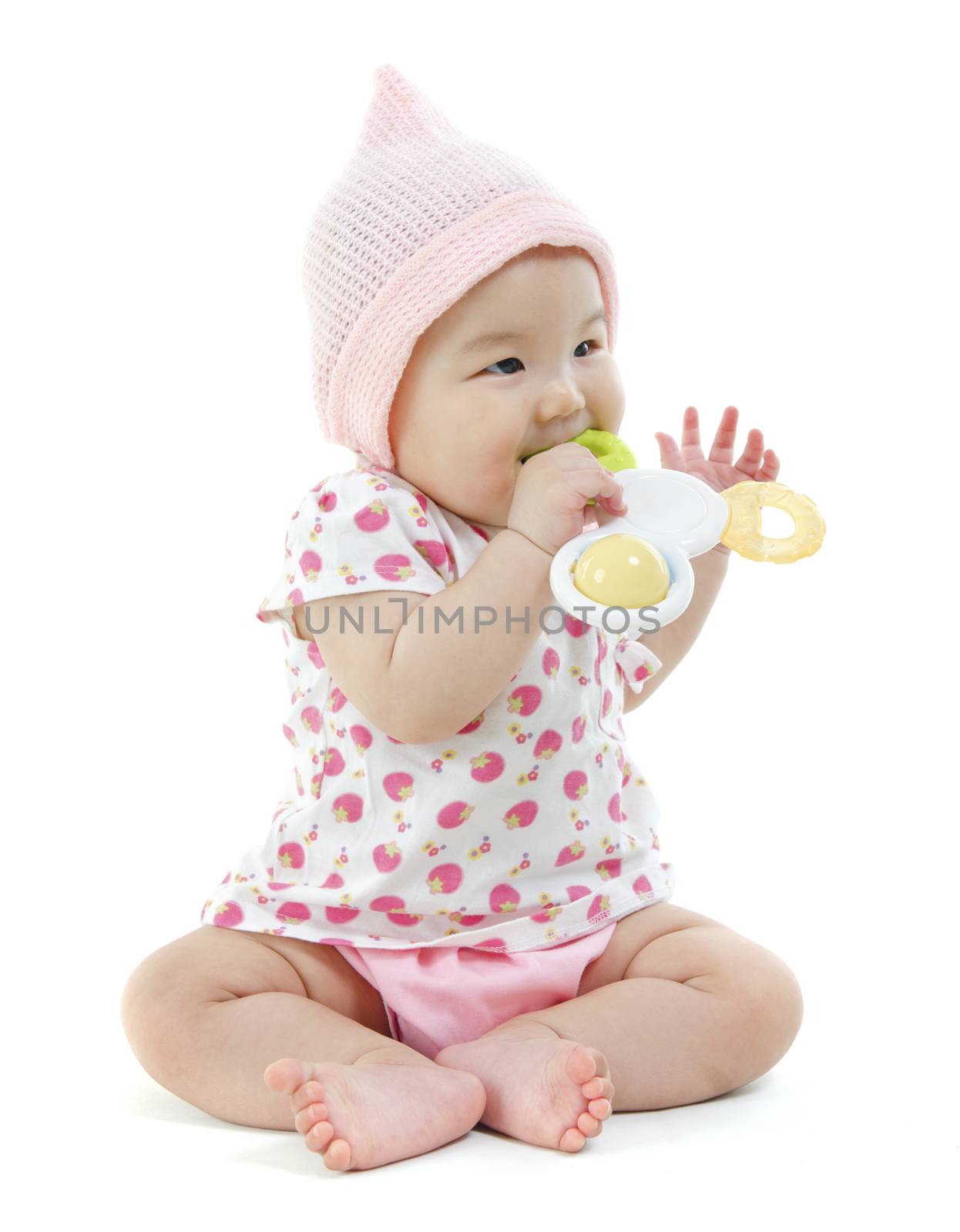 Portrait of full length beautiful Asian baby girl in pink clothes biting teething toy, isolated on white background.
