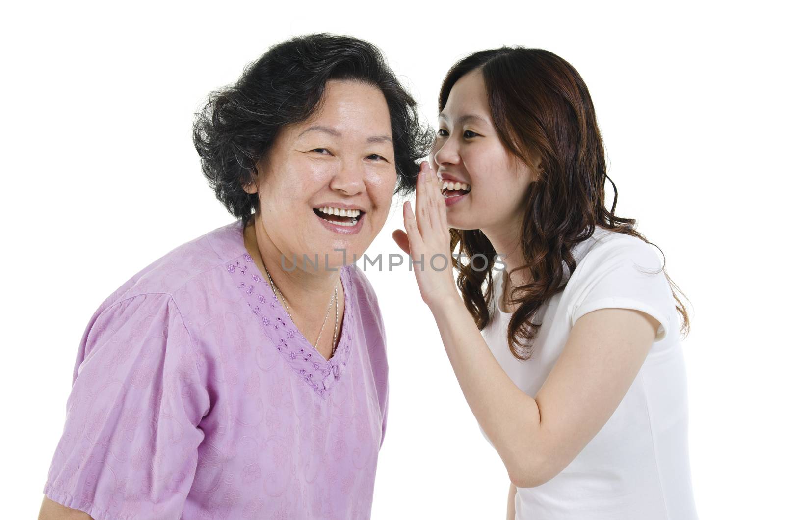 Portrait of Asian adult daughter telling secret to her senior mother, isolated on white background.