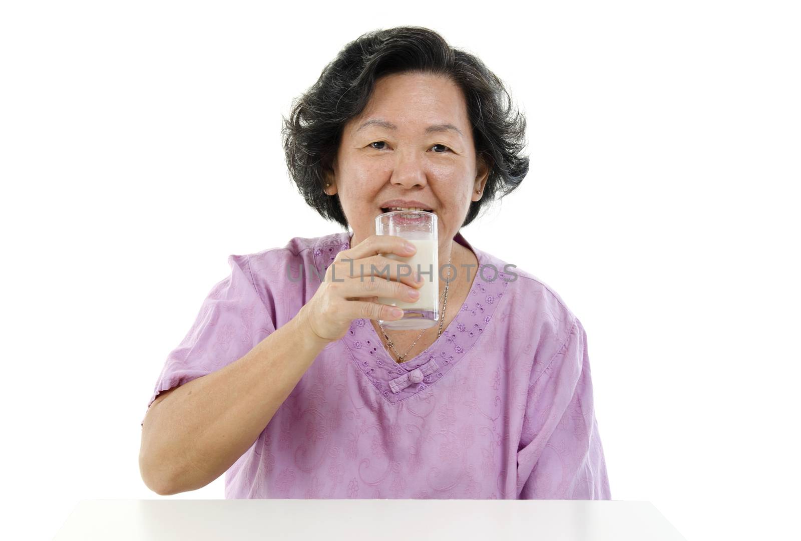 Portrait of happy Asian senior adult woman drinking a glass soy milk, isolated on white background.