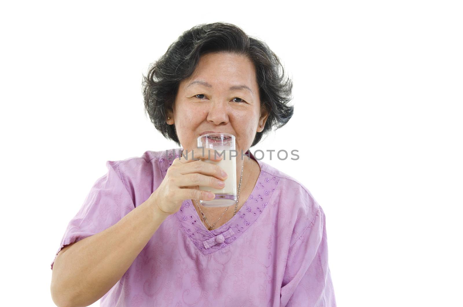 Portrait of Asian senior adult woman drinking a glass soy milk, isolated on white background.