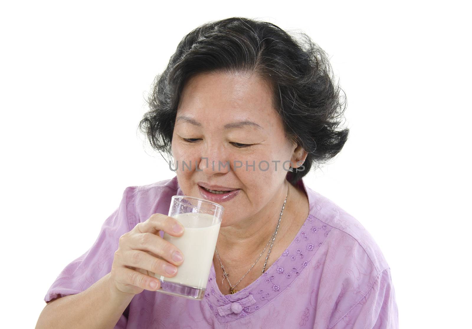 Portrait of healthy Asian senior adult woman drinking a glass soy milk, isolated on white background.