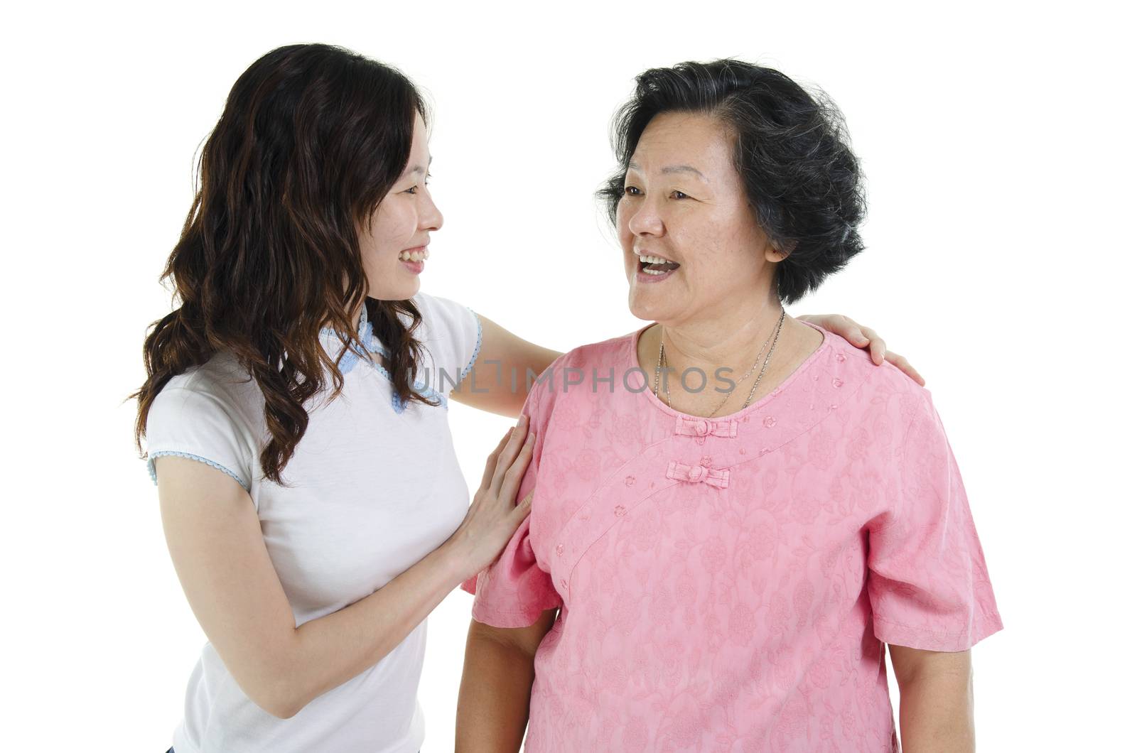 Portrait of Asian adult daughter and senior mother smiling looking at each other, isolated on white background.