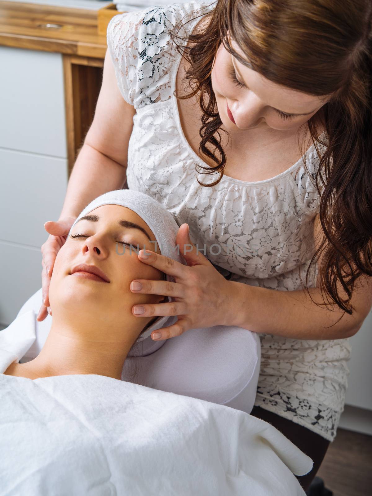 Photo of a young woman receiving a facial massage and treatment.