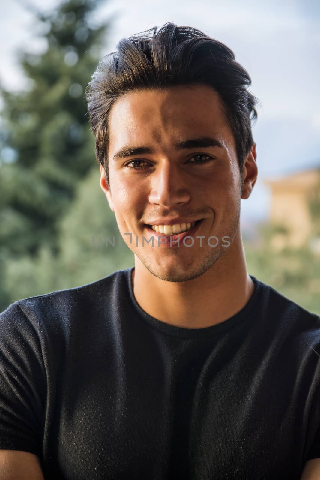 Headshot of handsome attractive young man smiling and looking at camera outdoor