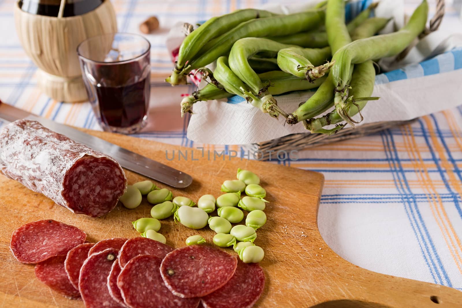 Chopping board with salami broad bean and a glass of red wine