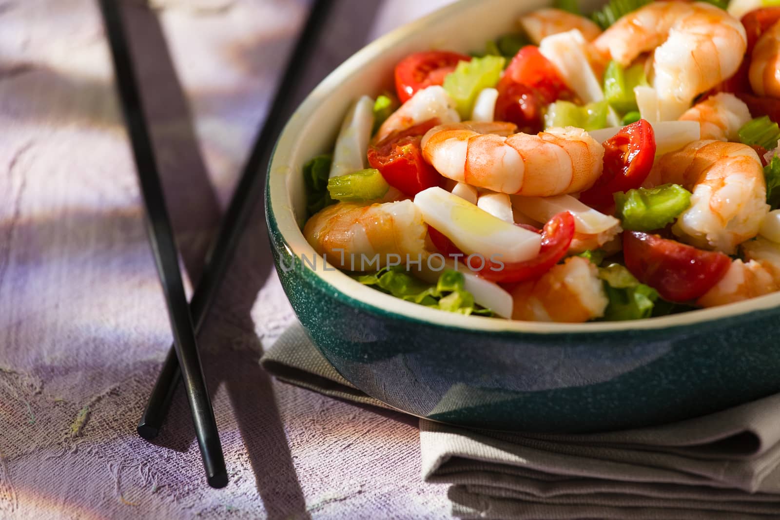 Close up of salad of shrimps and chopsticks inside an oval bowl