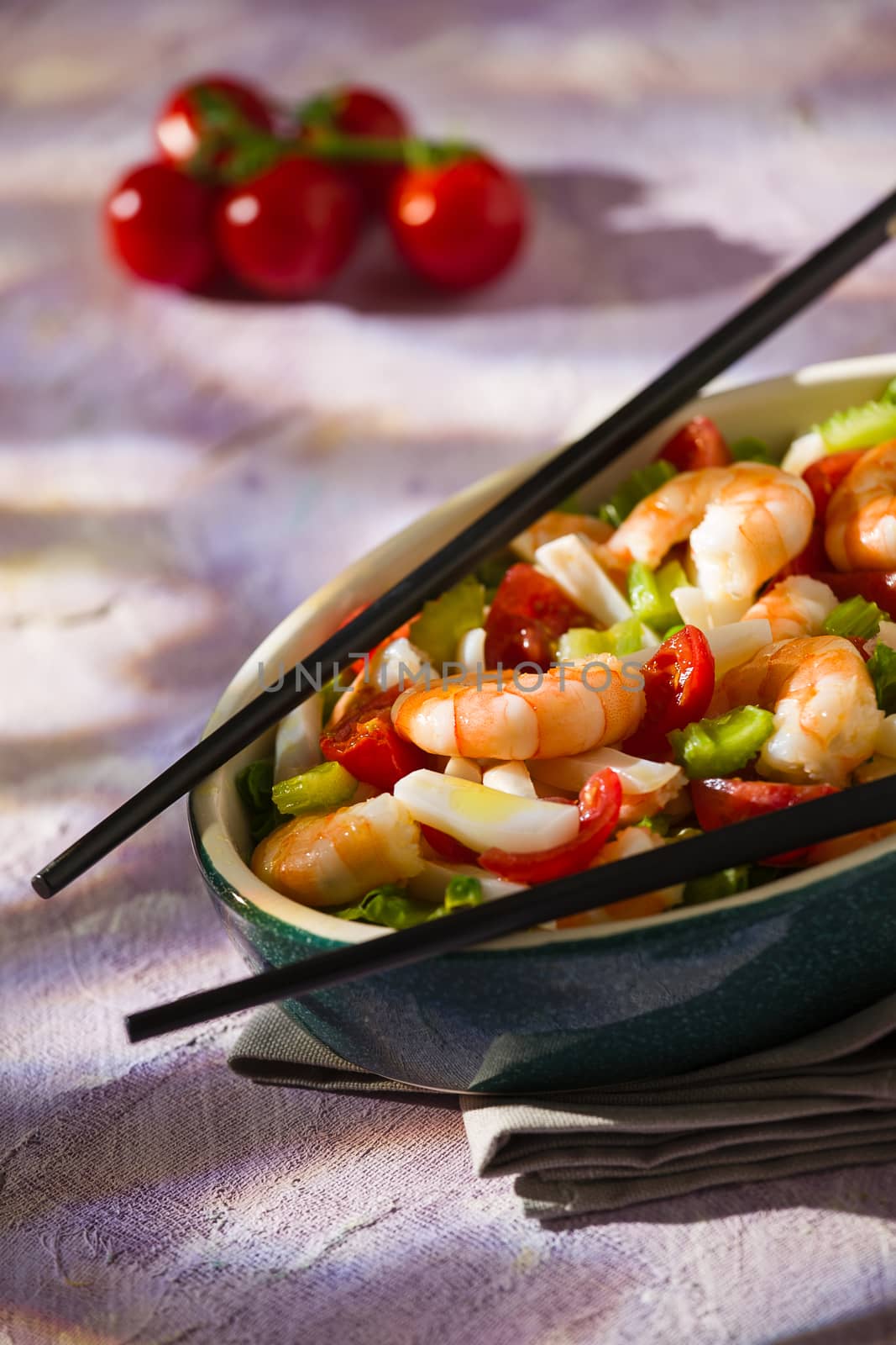 Salad of shrimps and chopsticks inside an oval bowl